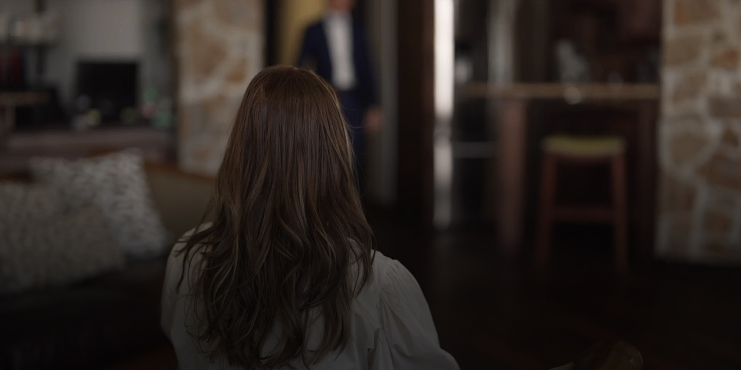 Person gazing at another in a dimly lit room.