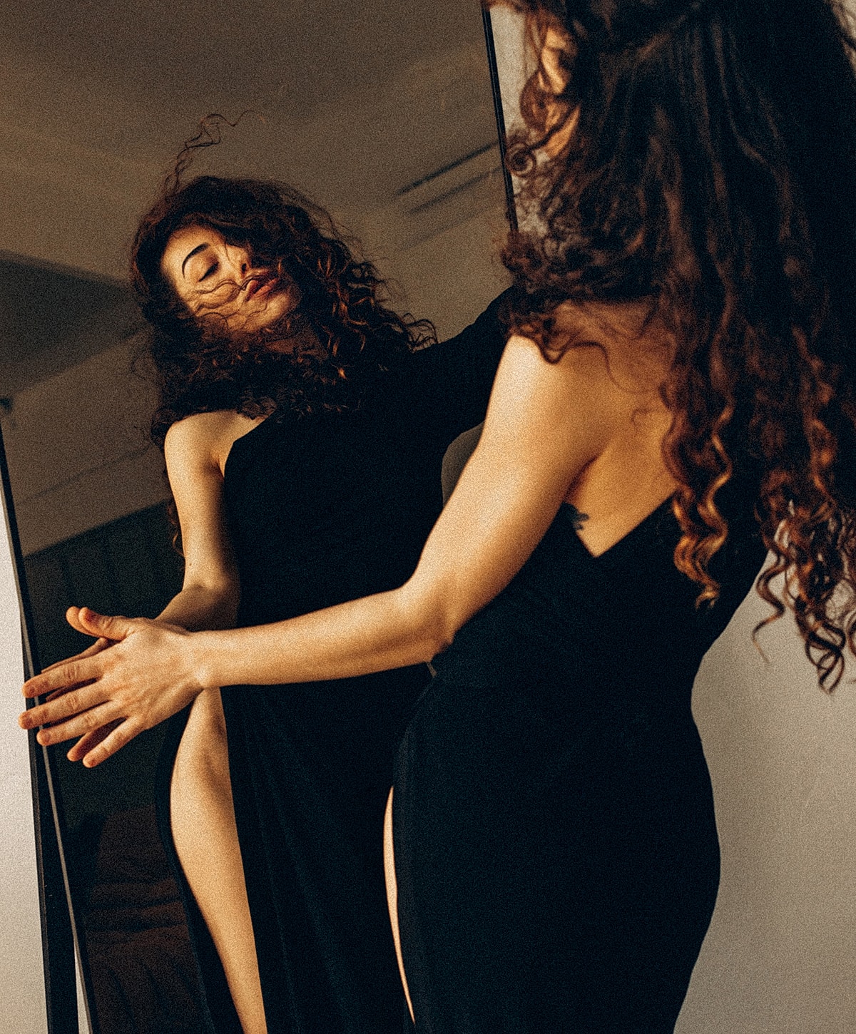 Woman posing gracefully in front of a mirror.