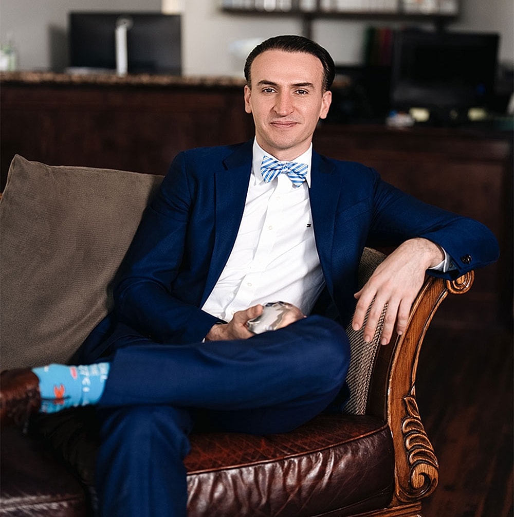Man in blue suit sitting on a sofa.