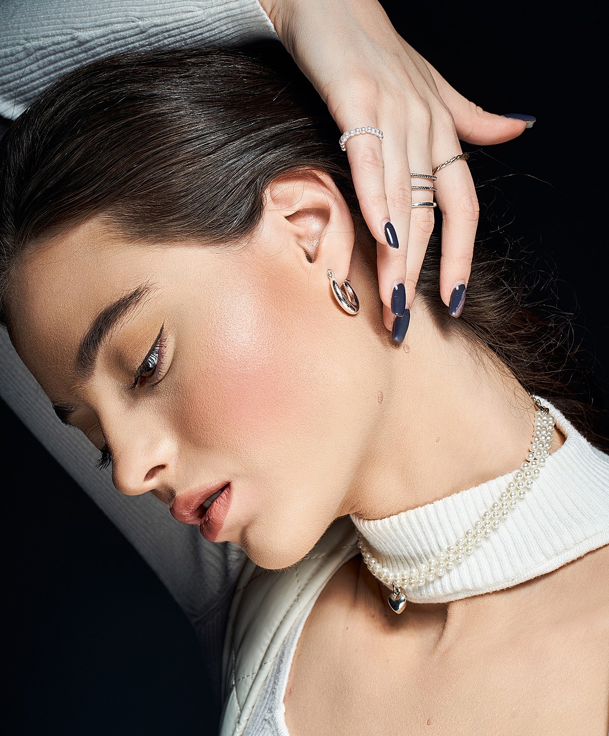 Woman showcasing elegant jewelry and hairstyle.