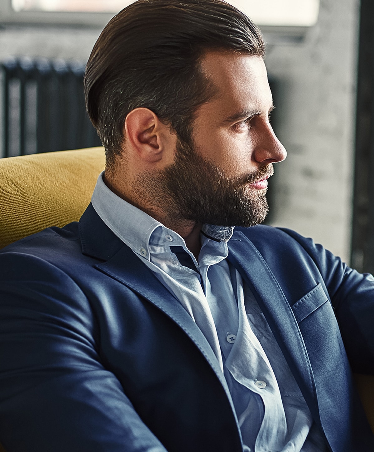 Man in suit sitting thoughtfully on a couch.