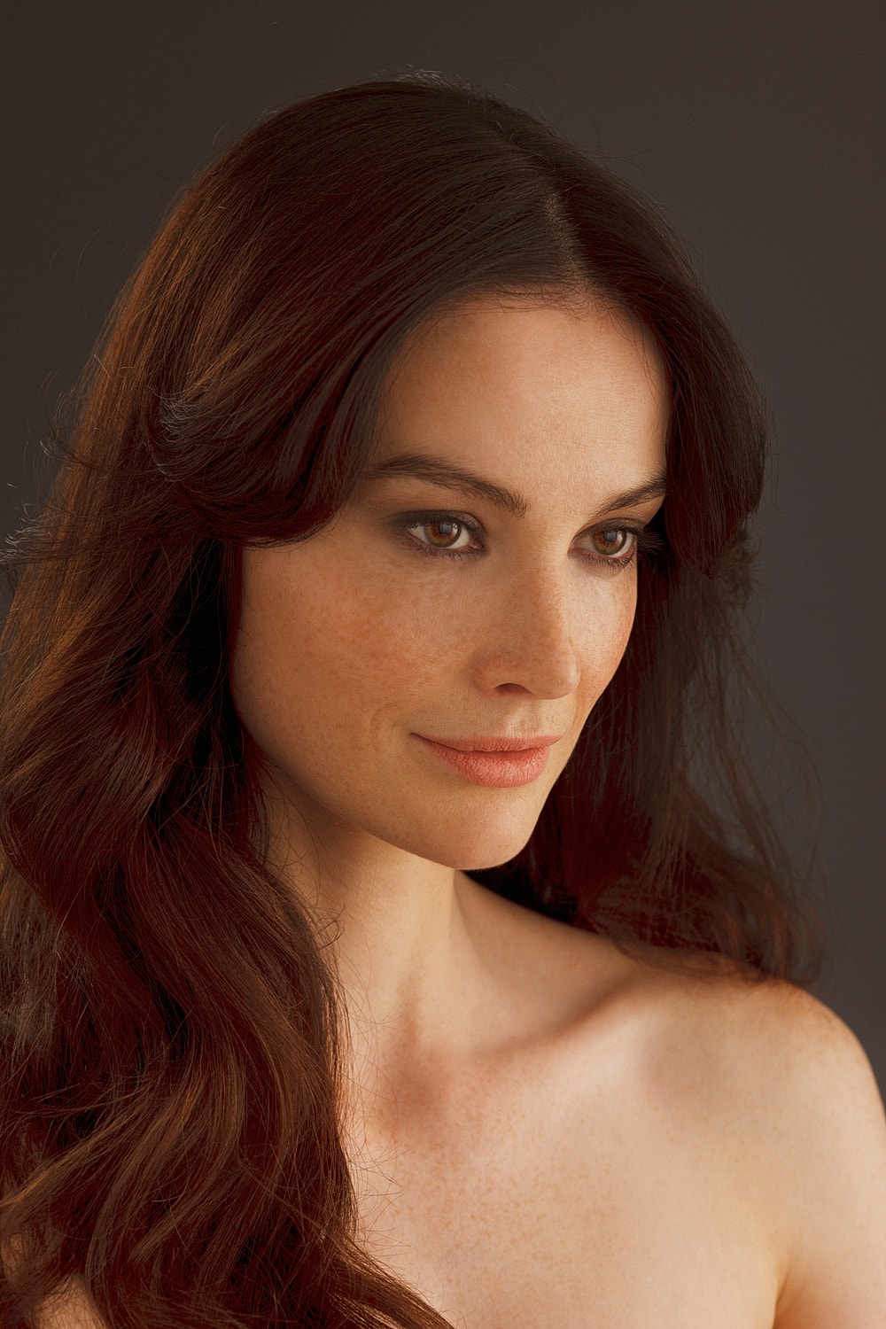 Woman with long, wavy dark hair and freckles.