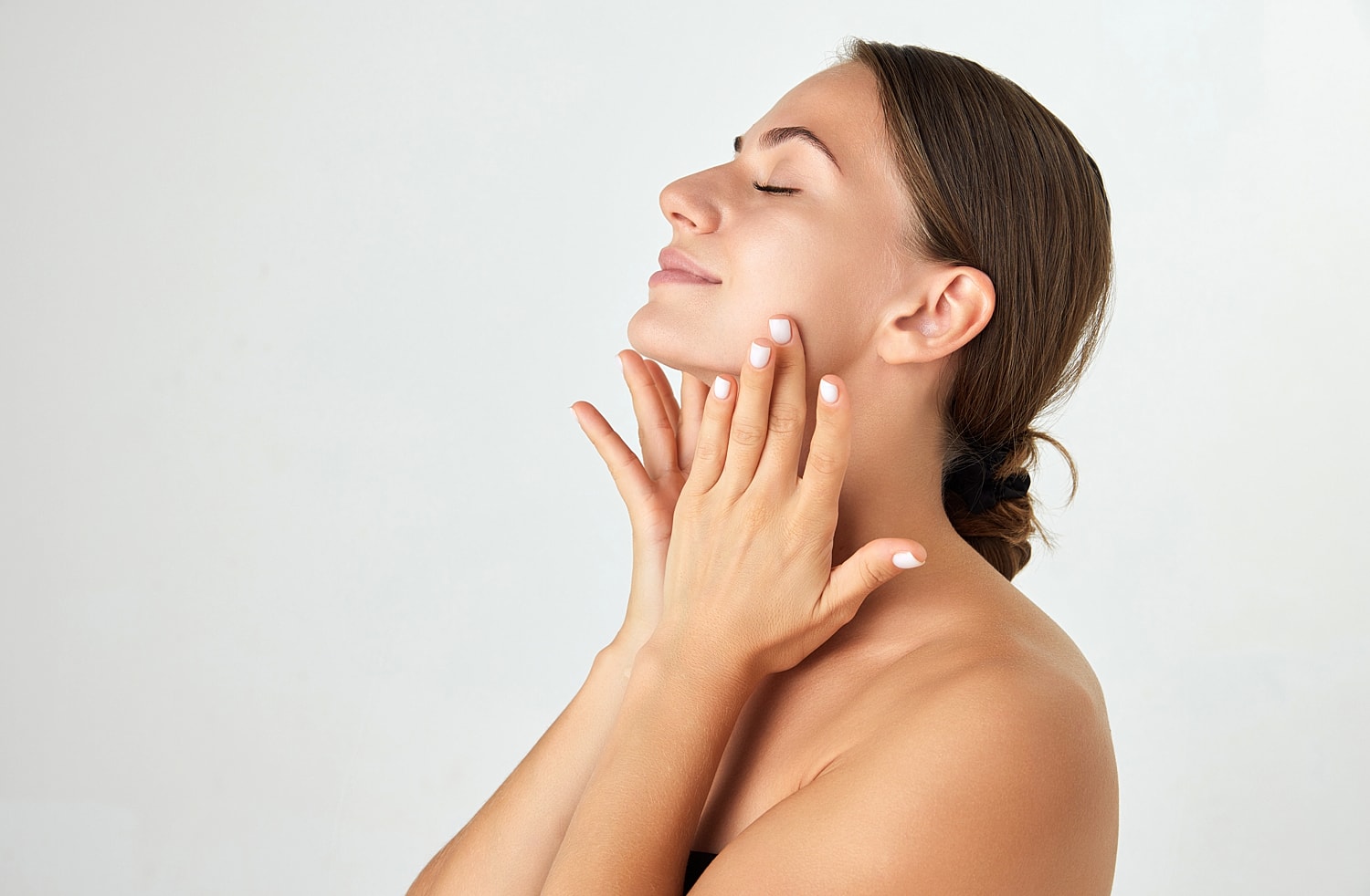 Woman gently touching her face and smiling.