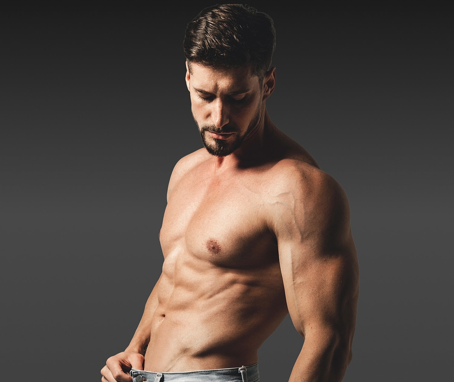 Muscular man posing against a dark background.