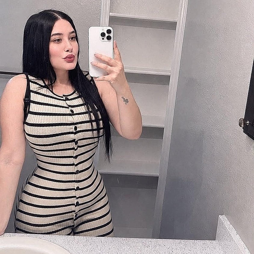 Woman posing in mirror wearing striped outfit.