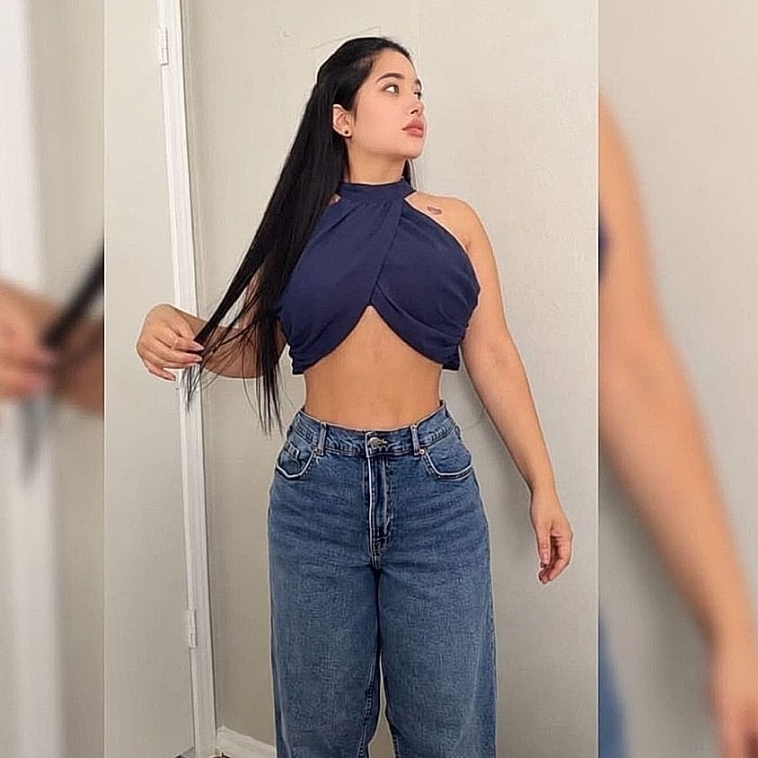 Woman posing in fashionable crop top and jeans.