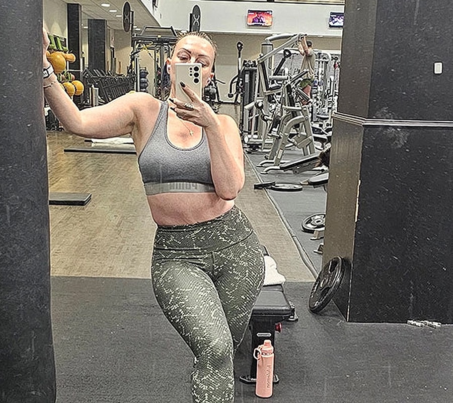 Woman taking mirror selfie in gym outfit.