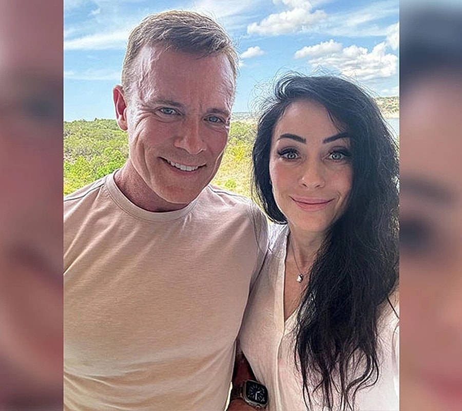 Smiling couple posing outdoors with lush background.