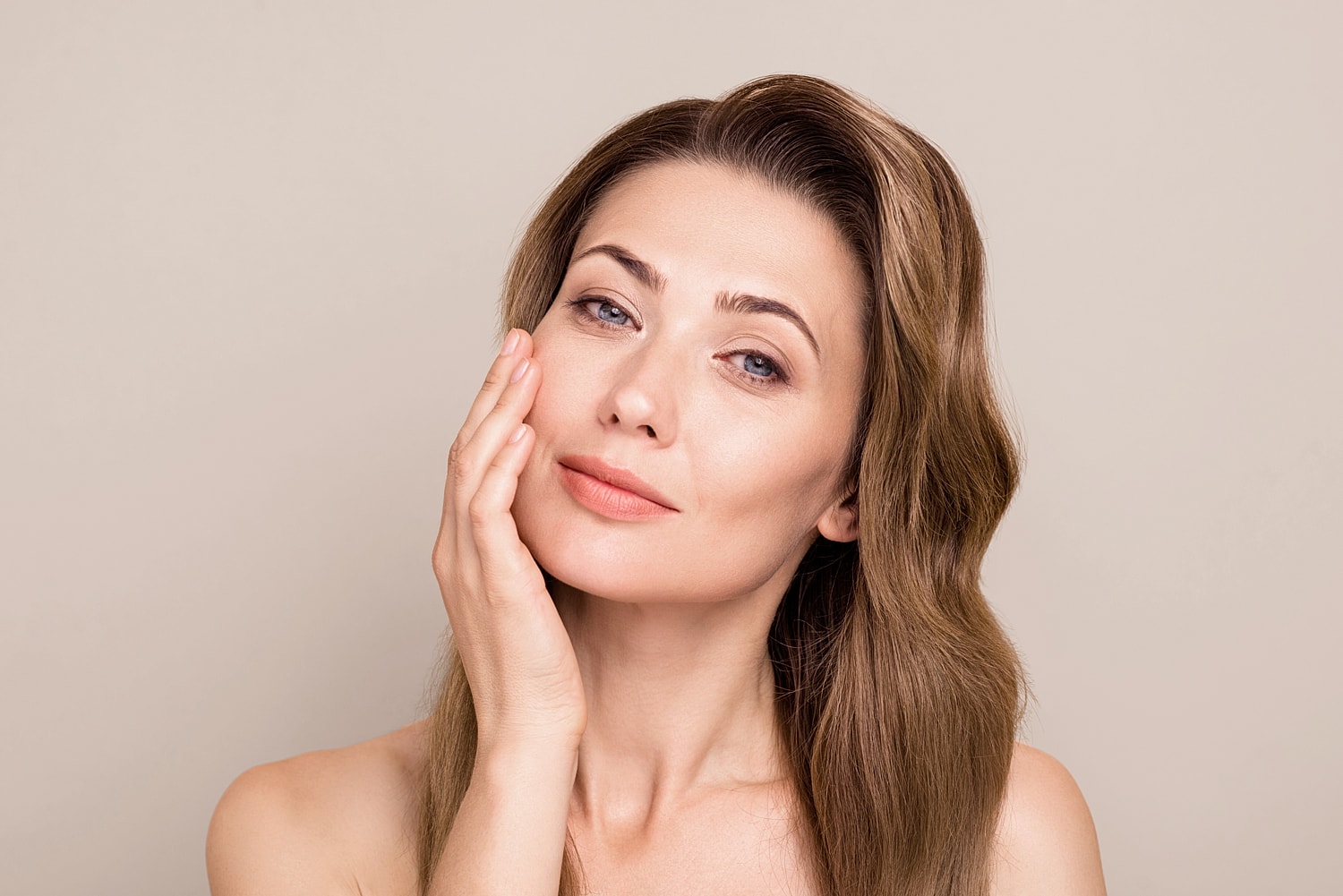 Woman touching her face with a soft expression.