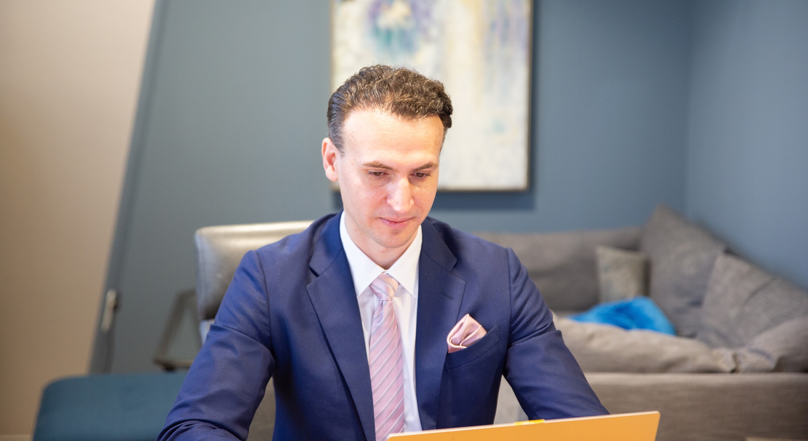 Man in suit working on laptop indoors.