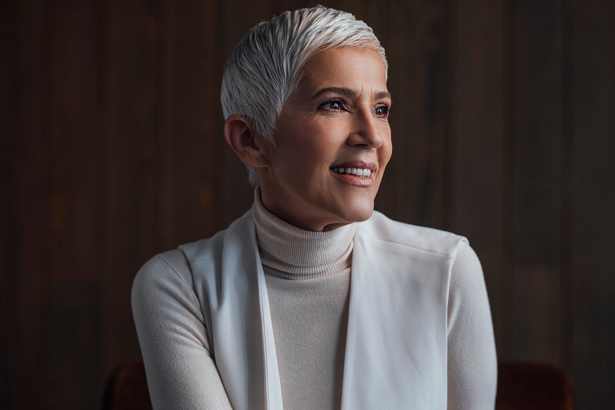 Smiling woman with short gray hair indoors.