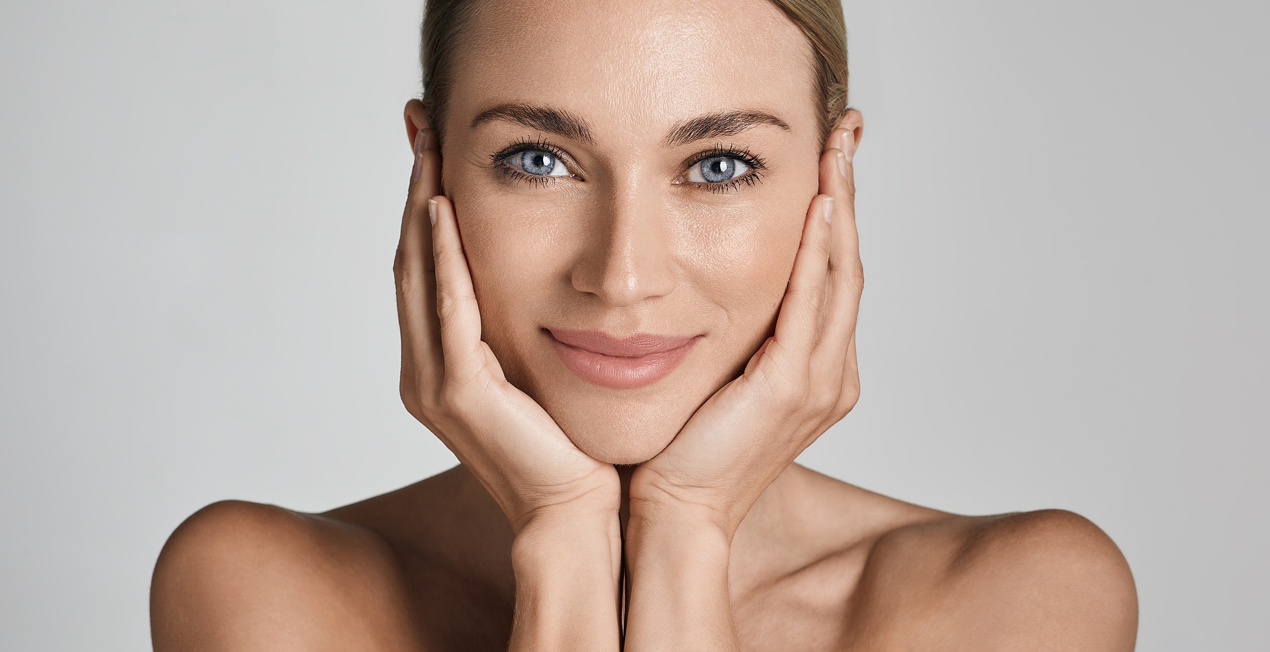 Smiling woman holding her face gently.