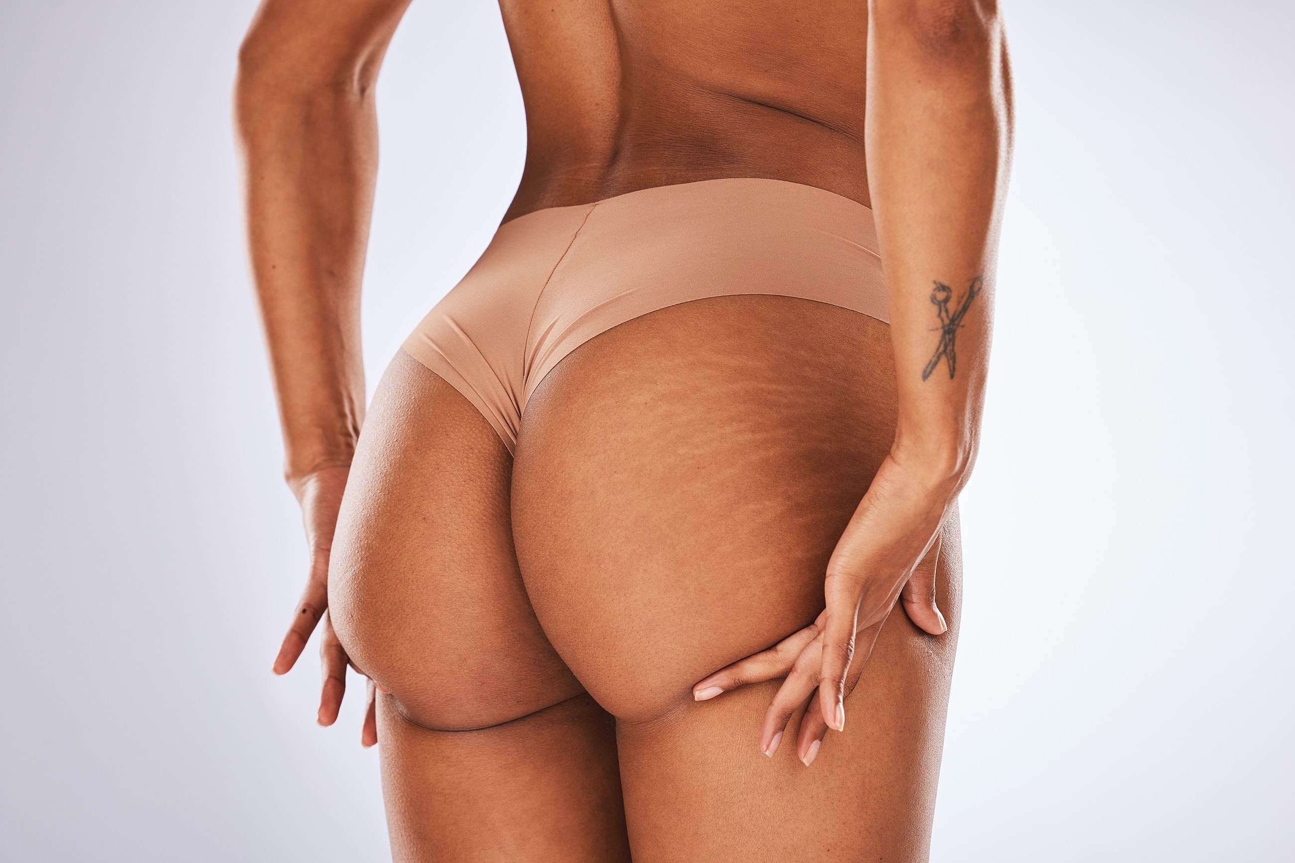 Model posing in minimalistic underwear, showcasing skin.